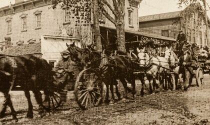 Heavy wagon teams on Main Street in front of the factory building