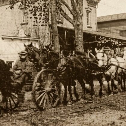 Heavy wagon teams on Main Street in front of the factory building